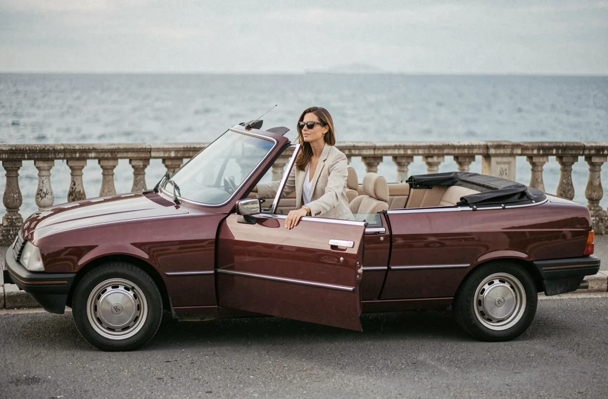 Femme appuyée sur une Peugeot 305 décapotable bordeaux sur une promenade côtière française
